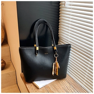 Détail d'un sac cabas vintage noir avec pompon perlé et ferrures dorées élégantes