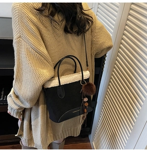 Détail du sac cabas noir avec bordure en fausse fourrure blanche, pompon brun et franges