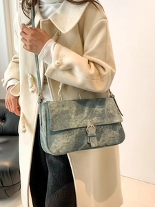 Sac bandoulière rétro à texture marbre avec boucle dorée porté par un mannequin