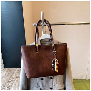 Détail du sac cabas marron foncé avec texture en cuir grainé et pompon en perles de bois