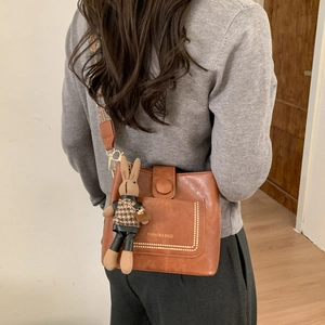 Brown crossbody bag with ethnic embroidered wide strap and rabbit plush pendant