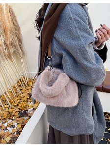 Gros plan du sac seau en peluche rose clair avec une fine bandoulière en cuir brun