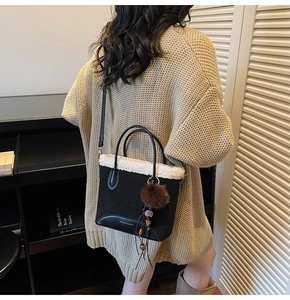 Détail d'un sac à bandoulière vintage noir avec bordure polaire et breloque peluche