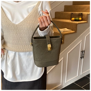 Detailed close-up of olive green bucket bag with gold metal clasp and lychee grain texture