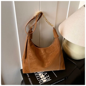 Detail of vintage brown frosted hobo bag with gold chain strap on art books