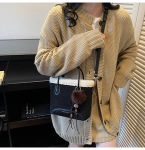 Détail du sac bandoulière noir avec bordure en mouton blanc et pompon marron en peluche