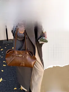 Detailed view of brown leather tote bag with contrast stitching and metal buckle detail