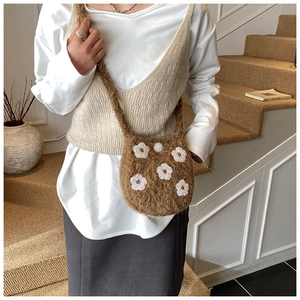 Detailed texture of brown plush crossbody bag with white flower embroidery details