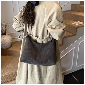Brown faux leather tote bag with stitch detail shown on shoulder of a model in a trench coat