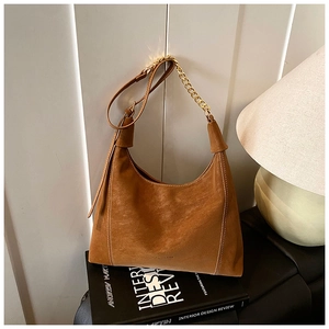 Close-up of caramel suede hobo bag with contrast stitching and gold chain detail
