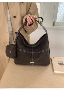 Detail of grey nubuck tote bag featuring contrast white stitching and mini charm pouch