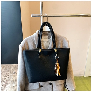 Détail du sac cabas en cuir grainé noir avec boucle dorée et breloque en perles colorées