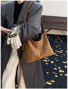 Close-up of brown suede tote bag with decorative stitching on grey blazer outfit