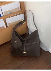 Detail of dark chocolate hobo bag with contrast stitching and small round coin purse