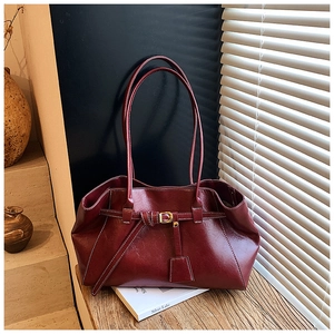 Detail view of burgundy tote bag featuring white contrast stitching and gold buckle hardware