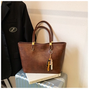 Détail du sac cabas vintage marron avec logo doré, perles en bois et cuir synthétique texturé