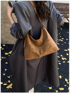 Close-up of a large brown suede hobo bag worn by a model in a fall setting