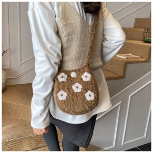 Detail of cute brown plush bucket bag with white floral embroidery and soft knit texture