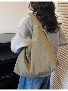 Minimalist olive green nylon crescent tote bag for women showing large capacity on model