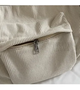 Detail of the high-quality metal zipper and textured corduroy fabric on a cream handbag