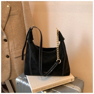 Detail of black suede bag with white contrast stitching and a decorative gold chain