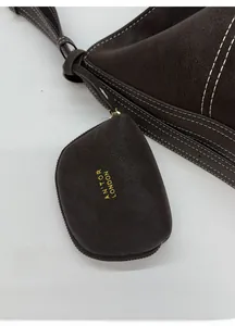 Detailed shot of dark brown leather tote with white stitching and mini charm pouch