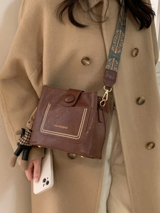 Vintage brown crossbody bag with bohemian wide strap and cute rabbit pendant on coat