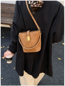 Detail view of brown matte bucket bag with gold clasp and adjustable shoulder strap