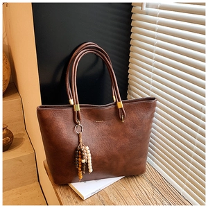 Détail du sac cabas marron vintage avec texture cuir, logo et breloque en perles