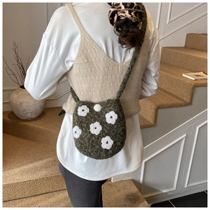 Detail of green plush bucket bag with white 3D flower embroidery and woven texture