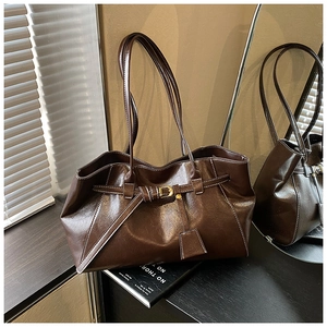 Detailed close-up of dark brown tote bag with metal buckle and glossy leather texture