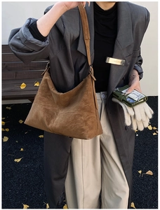 Macro detail of brown suede tote bag featuring distinctive cross stitching and wide strap