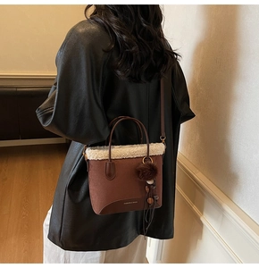 Détail du sac à bandoulière en daim marron avec bordure en fausse fourrure blanche et pompon