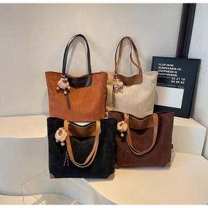 Detail of four colorful suede tote bags with leather handles and plush charm accessories