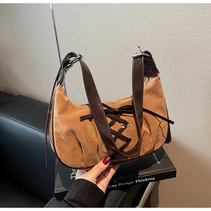 Detailed close-up of brown suede hobo bag with lace-up straps and glossy leather handle