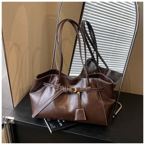 Detail of dark brown tote bag featuring white contrast stitching and matte gold hardware