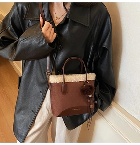 Détail du sac seau en daim marron avec garniture en peau de mouton et pompon doux