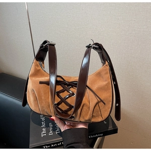 Detailed view of suede hobo bag featuring lace-up patent leather and silver metal buckles