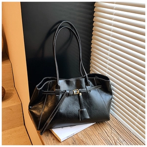 Close-up of black tote bag with white contrast stitching and gold metal buckle detail
