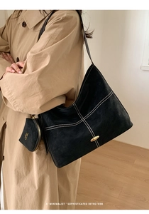Macro shot of black matte tote bag featuring contrast stitching and gold metal buckle