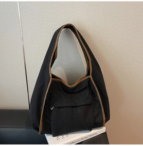 Detail view of black corduroy tote bag with brown fabric trim and front flap pocket