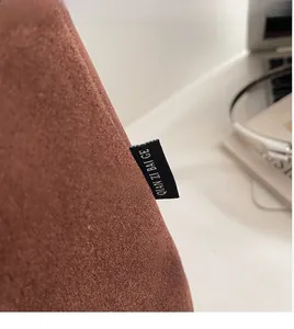 Detail view of the brown suede fabric and brand logo label on the large shoulder bag