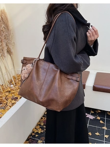 Brown suede tote bag worn over the shoulder featuring a cute plush bear charm detail