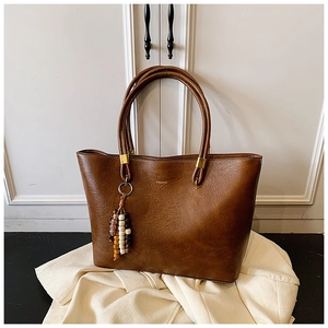 Détail d'un sac cabas marron en similicuir avec logo doré et perles en bois colorées