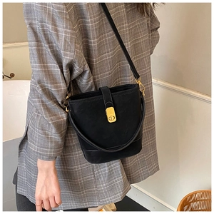 Detail of a chic black bucket bag with gold hardware worn over a grey plaid blazer