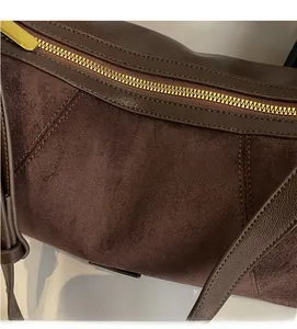 Détail des coutures et de la fermeture éclair en métal doré du sac en daim marron