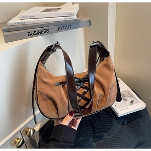 Detail of brown suede crescent bag featuring vintage ribbon tie straps and pleated texture