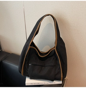 Detail of black corduroy shoulder bag with brown trim and silver zipper pocket