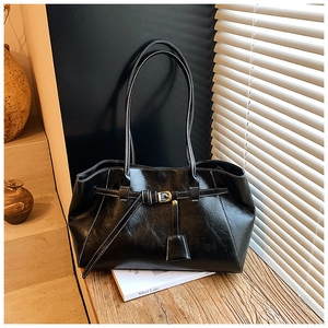 Detail of vintage black tote bag with white stitching and leather buckle on wooden desk