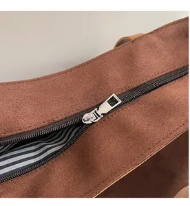 Close-up of smooth silver zipper and blue striped fabric lining on a brown tote bag